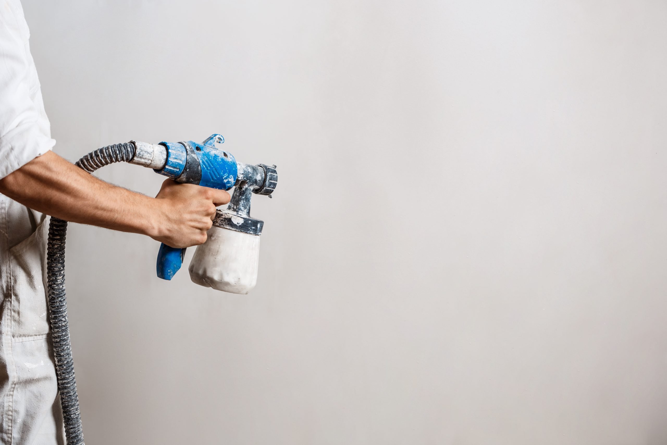 Homem pintando parede com pistola de pintura/Airless